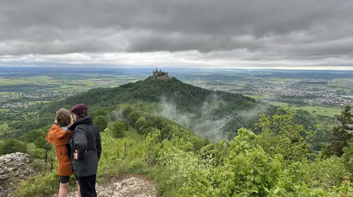 Zwei Wanderer blicken aus der Ferne auf die Zollernburg | © Claudia Endriss